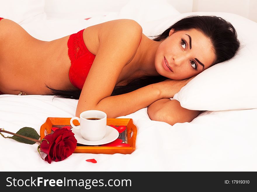 Girl lying in bed with gifts, cards, hearts, coff