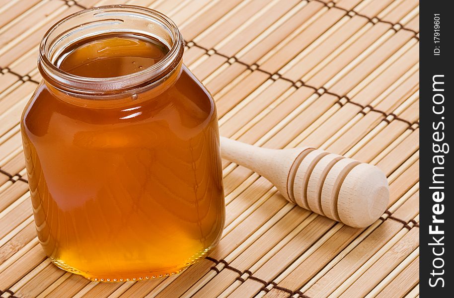 Glass pot of honey and wooden stick