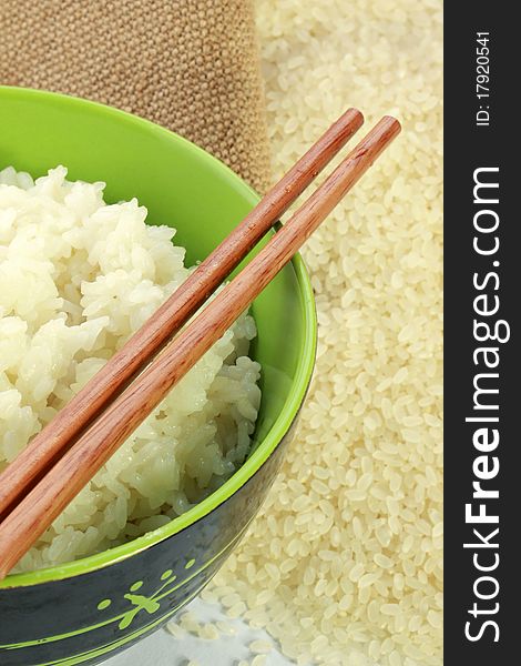 A bowl of rice and a pile of uncooked rice closeup