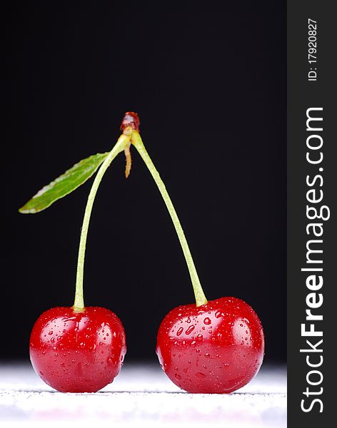 Two cherries against dark background