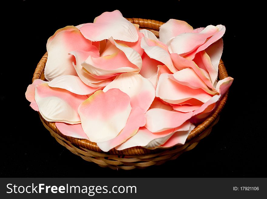 Artificial pink rose textile petals in basket on black. Artificial pink rose textile petals in basket on black