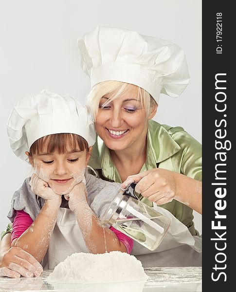 Happy, blond caucasian mother and daughter preparing dough and having fun