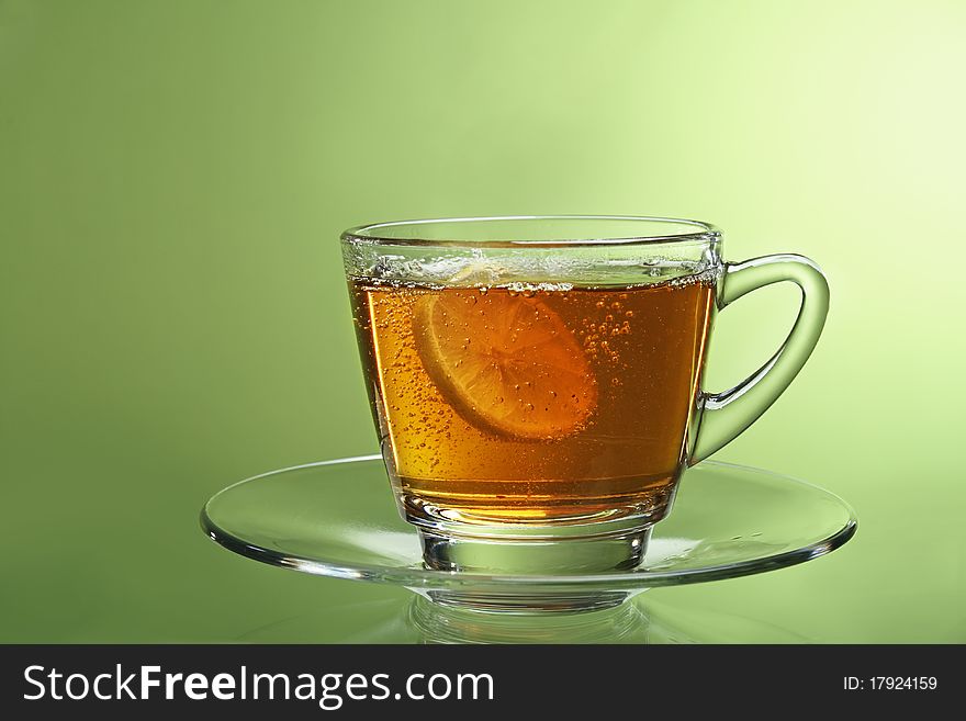 Lemon tea in the glass cup on green background