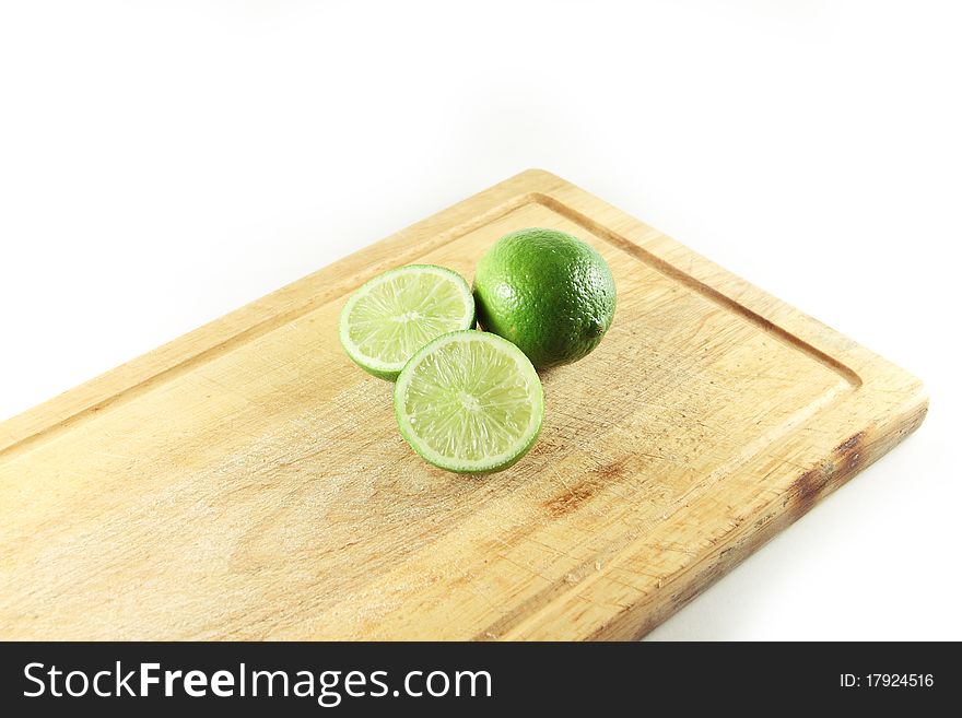 Two green limes on a light cutting board isolated. Two green limes on a light cutting board isolated