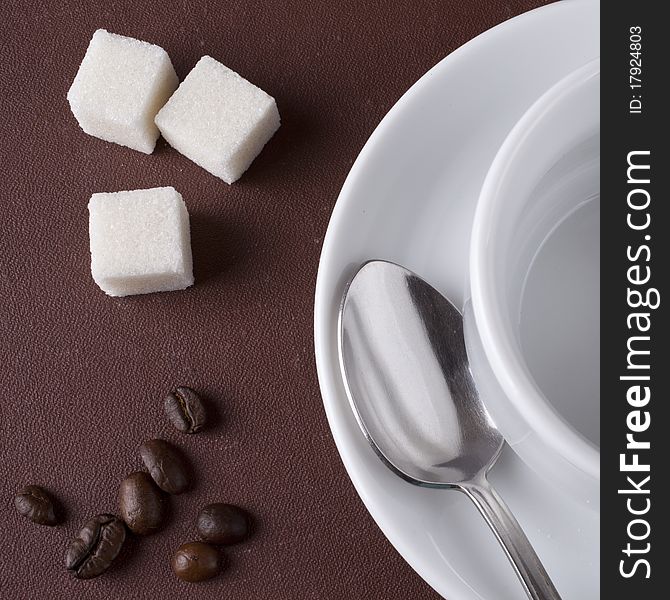 White cup with coffee grains on a brown background. White cup with coffee grains on a brown background