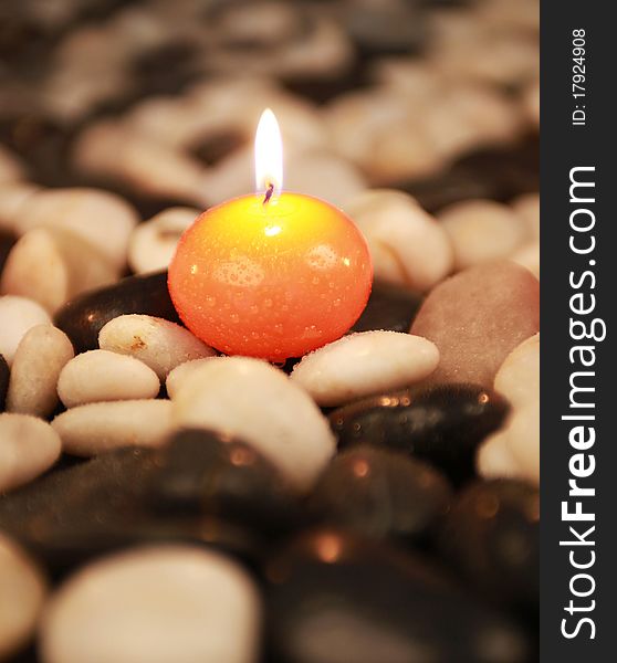 Orange candle on white and black stones