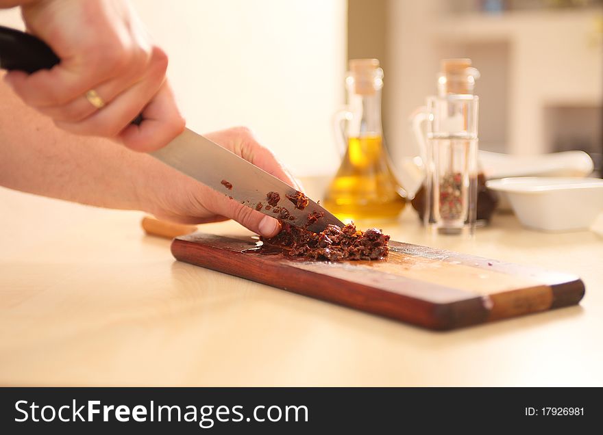 Chef cutting sundried tomatoes on board