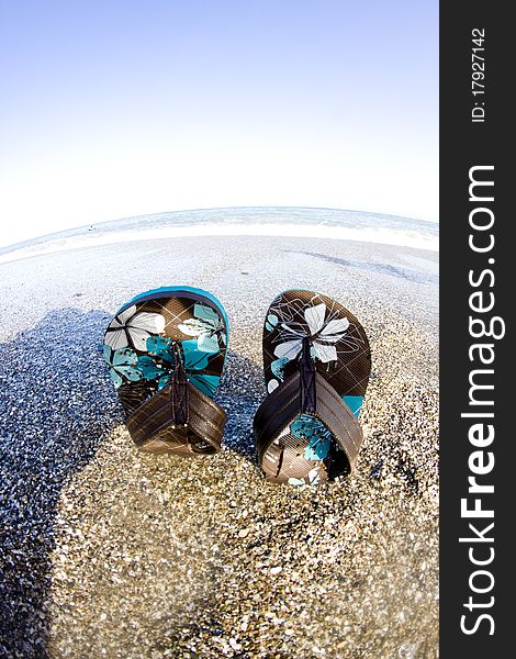 Flip flop on sandy beach in front of the sea fish eye look. Flip flop on sandy beach in front of the sea fish eye look