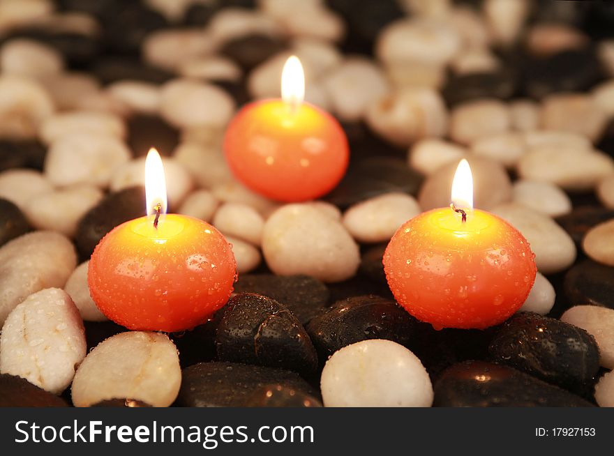 Triangle of orange candles on stones