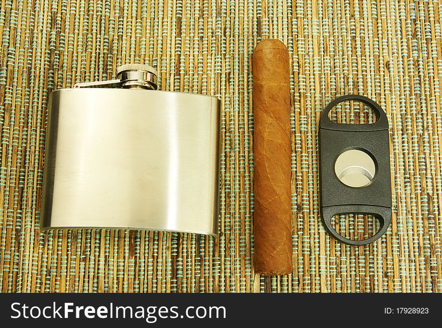 Close up of cigar, cigar cutter and hip flask. Close up of cigar, cigar cutter and hip flask