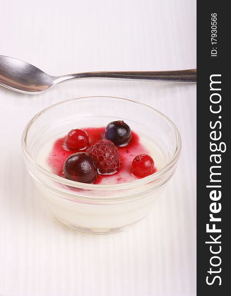 Panna cotta with soft fruits served in a small glass bowl