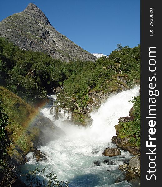 Waterfall in the Lodalen Valley, lake Lovatnet. Loen, Stryn, Norway. (Blurred background). The Lodalen valley has a dramatic history. Giant boulders have twice (1905 and 1936) broken off Mount Ramnefjell and fallen into the Lovatnet lake, creating tidal waves that destroyed the villages of Nesdal and Bodal. Waterfall in the Lodalen Valley, lake Lovatnet. Loen, Stryn, Norway. (Blurred background). The Lodalen valley has a dramatic history. Giant boulders have twice (1905 and 1936) broken off Mount Ramnefjell and fallen into the Lovatnet lake, creating tidal waves that destroyed the villages of Nesdal and Bodal.