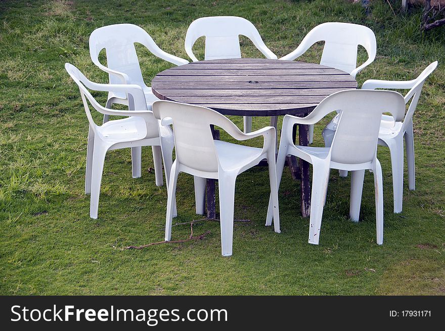 White folding chairs and a table on a background of grass. White folding chairs and a table on a background of grass