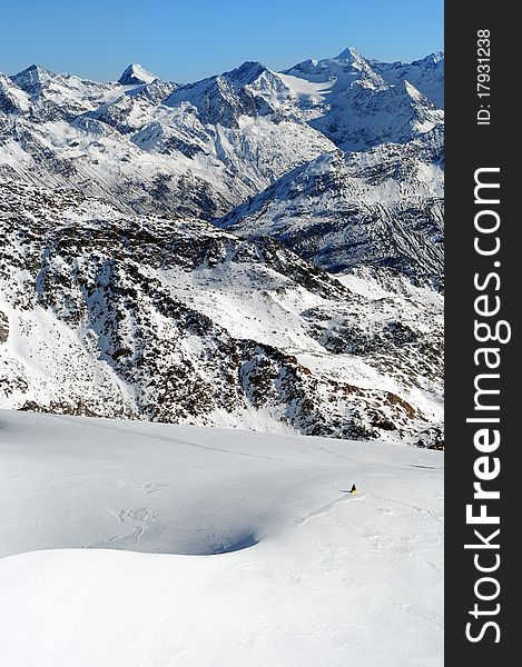 Scenic view of Austrian Alps. Snowboarder freeriding fresh snow down right. Scenic view of Austrian Alps. Snowboarder freeriding fresh snow down right.