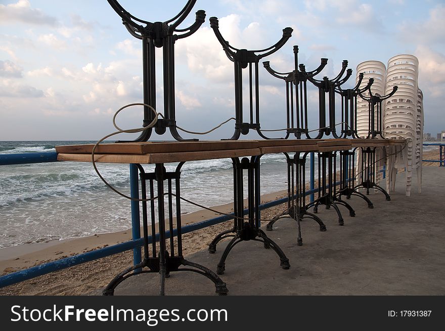 Stacked tables and chairsagainst the backdrop of the sea