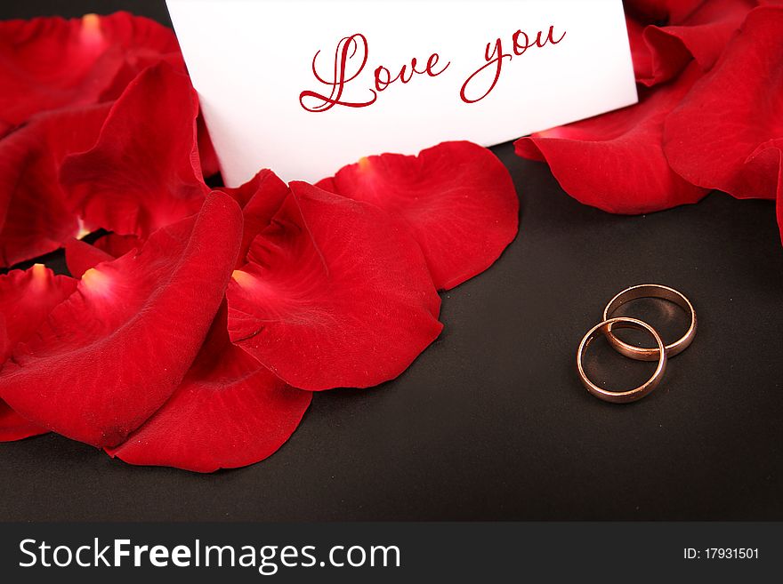 Two wedding rings and red petals. Two wedding rings and red petals