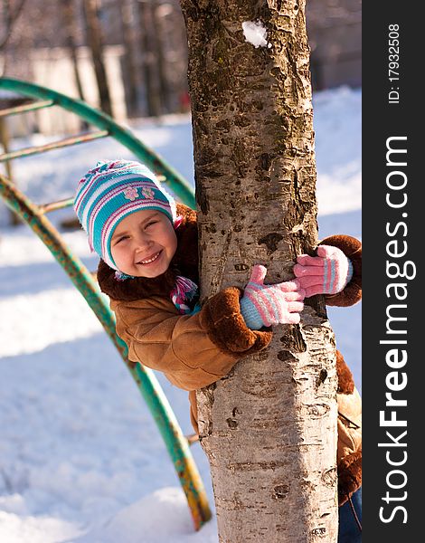 Beautiful girl hugging a tree in winter