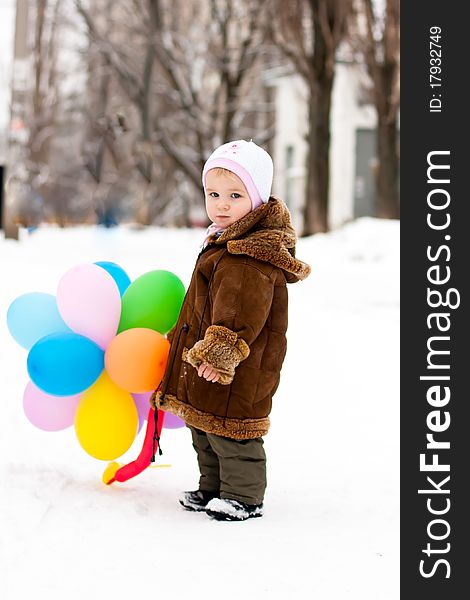 Beautiful girl playing with balloons outdoor in winter