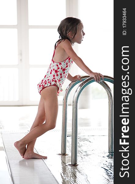 Young girl stand near to indoor swimming pool. Young girl stand near to indoor swimming pool