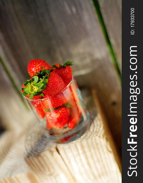 Strawberry in glass in front of wood and on wood, village raw food