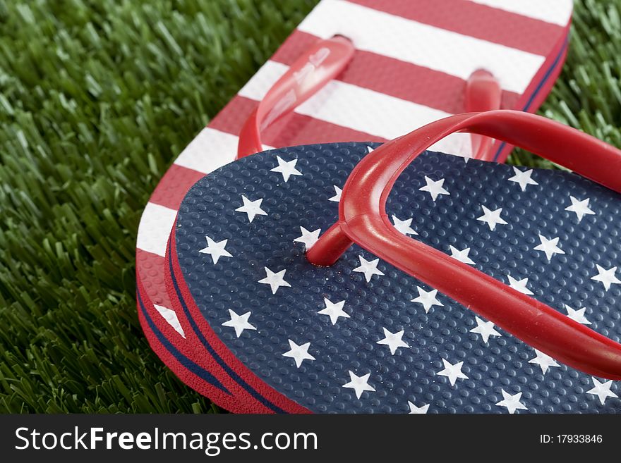 A pair of USA stars and strips flipflops in the grass. A pair of USA stars and strips flipflops in the grass