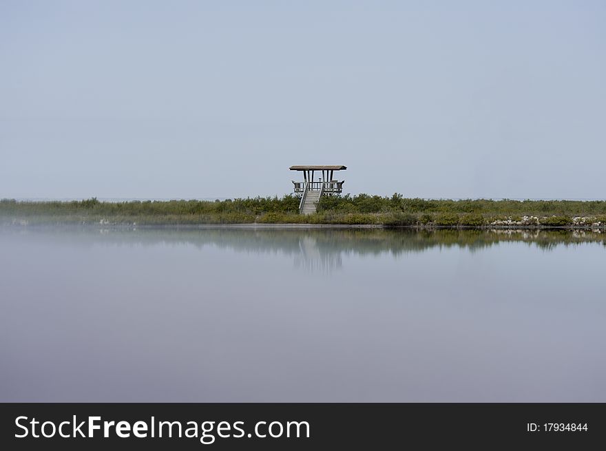 An observation tower in a wildlife preserve in Florida in a light fog reflecting in water. An observation tower in a wildlife preserve in Florida in a light fog reflecting in water.