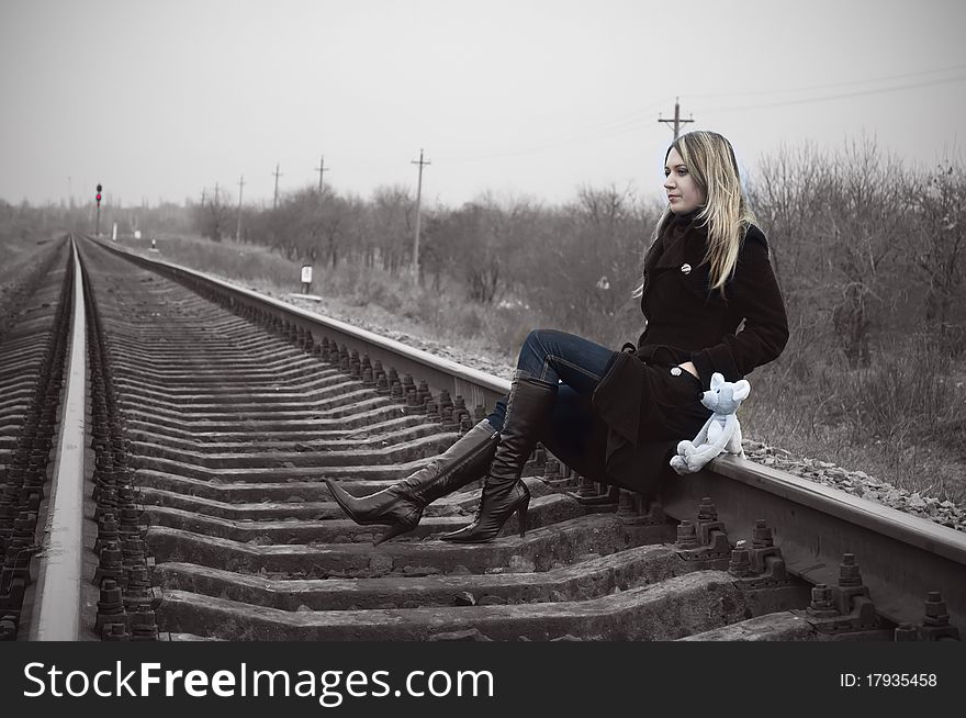 The girl sits on rails with the toy mouse. The girl sits on rails with the toy mouse