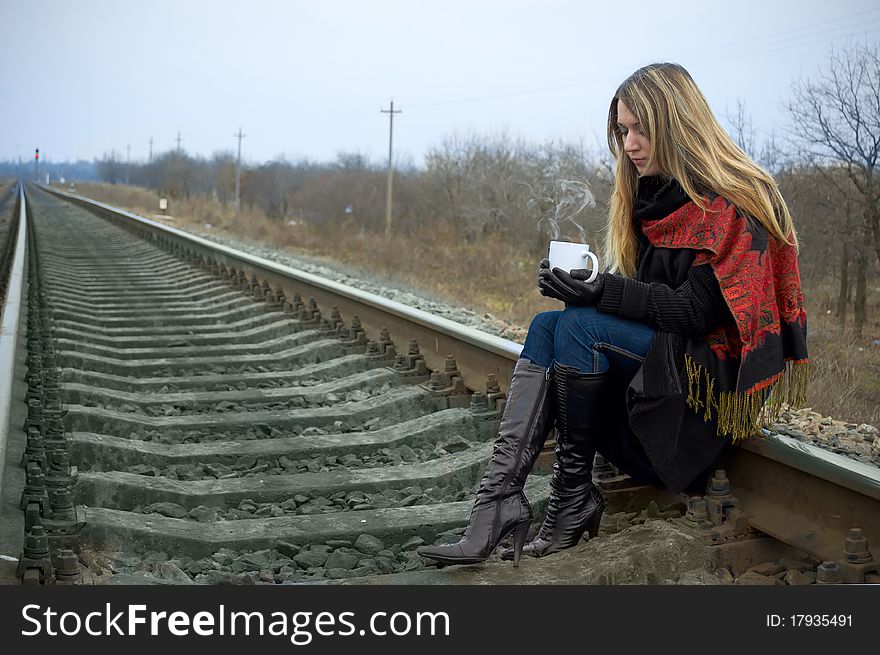 The girl with a cup sits on rails