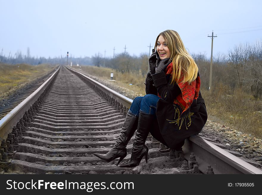 The girl sits on rails and speaks by phone. The girl sits on rails and speaks by phone