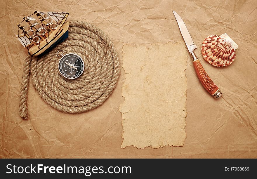 Rope coil, decorative knife and model classic boat on old paper. Rope coil, decorative knife and model classic boat on old paper