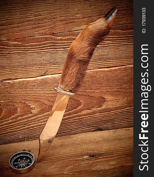 Knife and compass on wood background