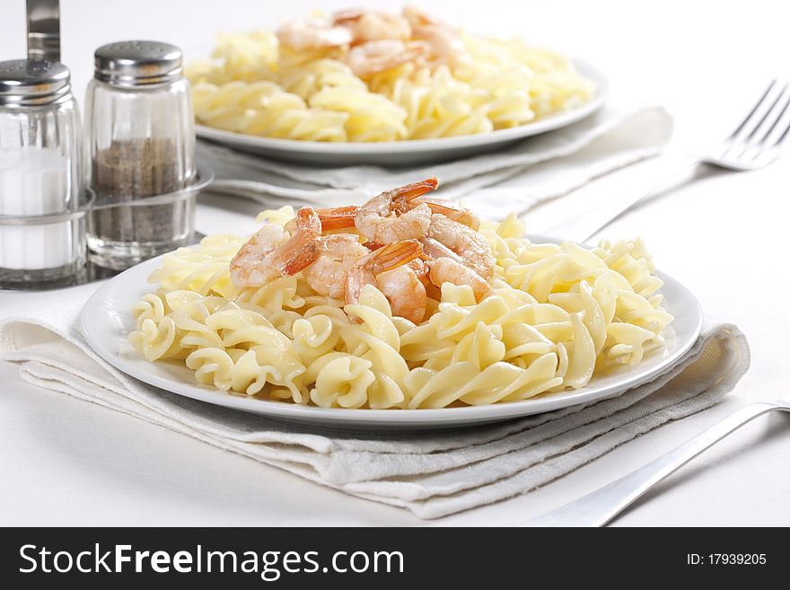 Two plates of pasta with prawns