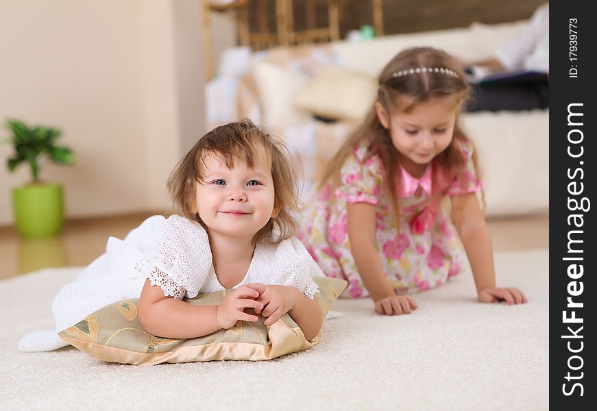 Two little sisters together playing on the floor of a livingroom