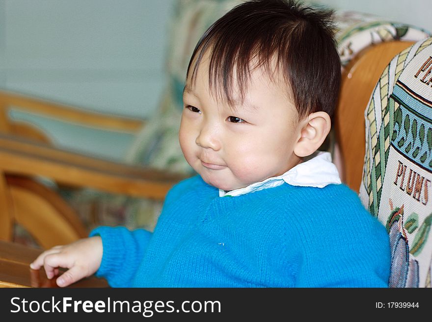 A chinese boy with confident face sitting on sofa at home. A chinese boy with confident face sitting on sofa at home