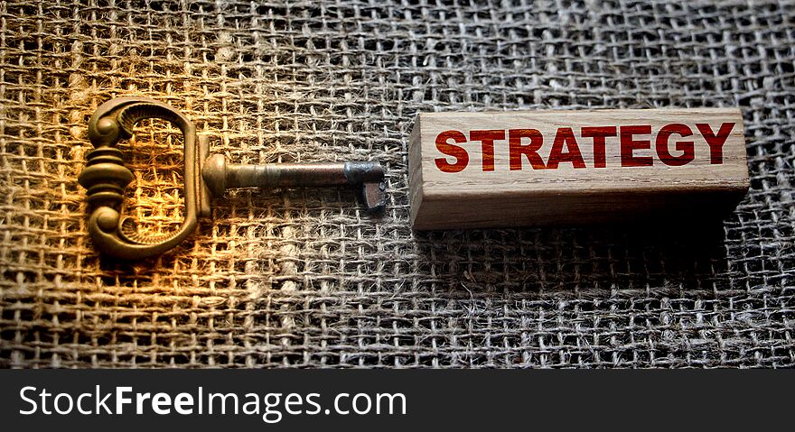 Keys to Strategy. Vintage key and Strategy word on wooden block on burlap canvas. Business planning concept.