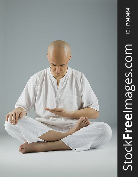 Male dressed in white sitting in meditation position, looking down. Male dressed in white sitting in meditation position, looking down