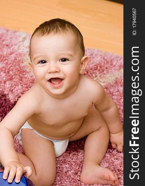 Smiling caucasain baby sitting on the carpet