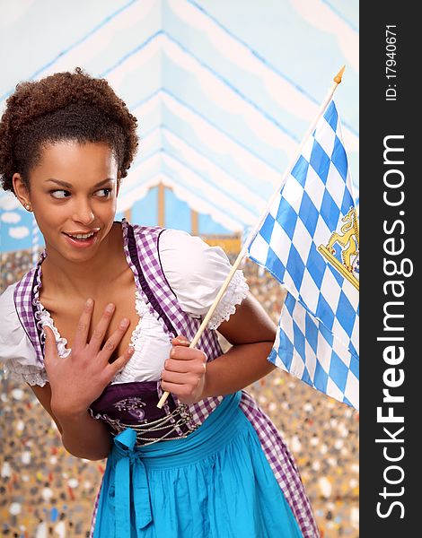 Dark skinned girl wearing a traditional bavarian dress holding a flag. Dark skinned girl wearing a traditional bavarian dress holding a flag
