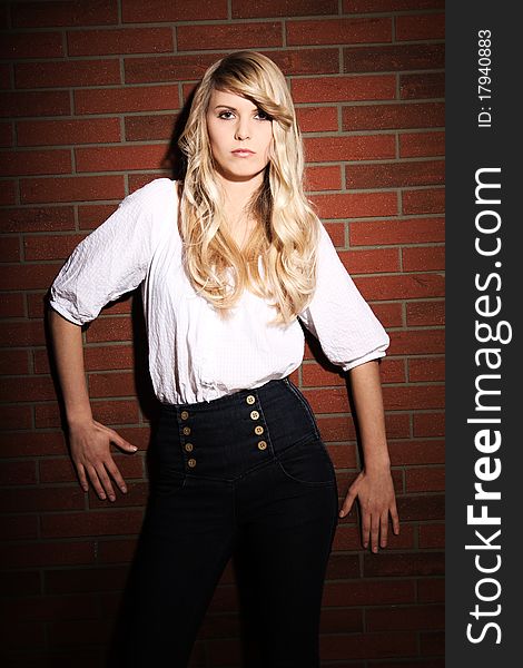 Beautiful blond girl is posing in front of a brick wall. Beautiful blond girl is posing in front of a brick wall