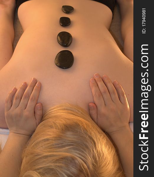 Young woman having a hot stone back massage. Young woman having a hot stone back massage