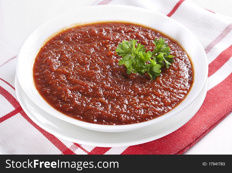 Tomato soup with parsley in a bowl on white background