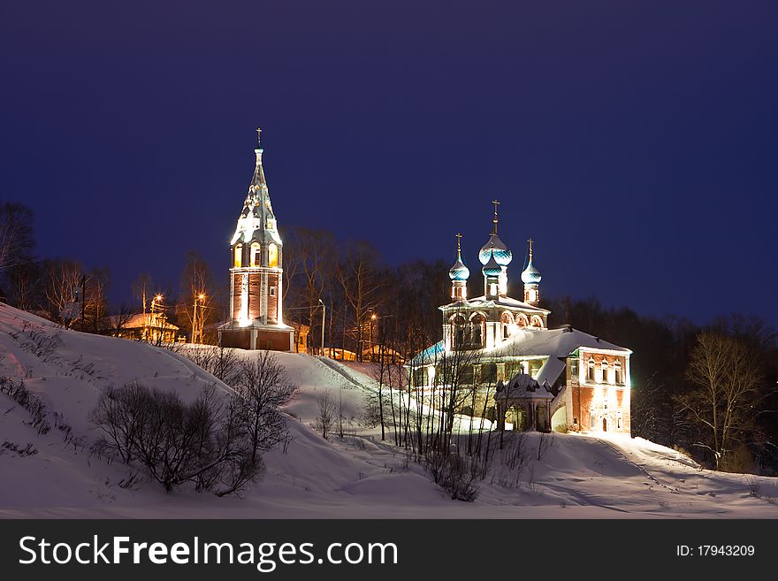 Brightly illuminated church on the bank of the frozen river