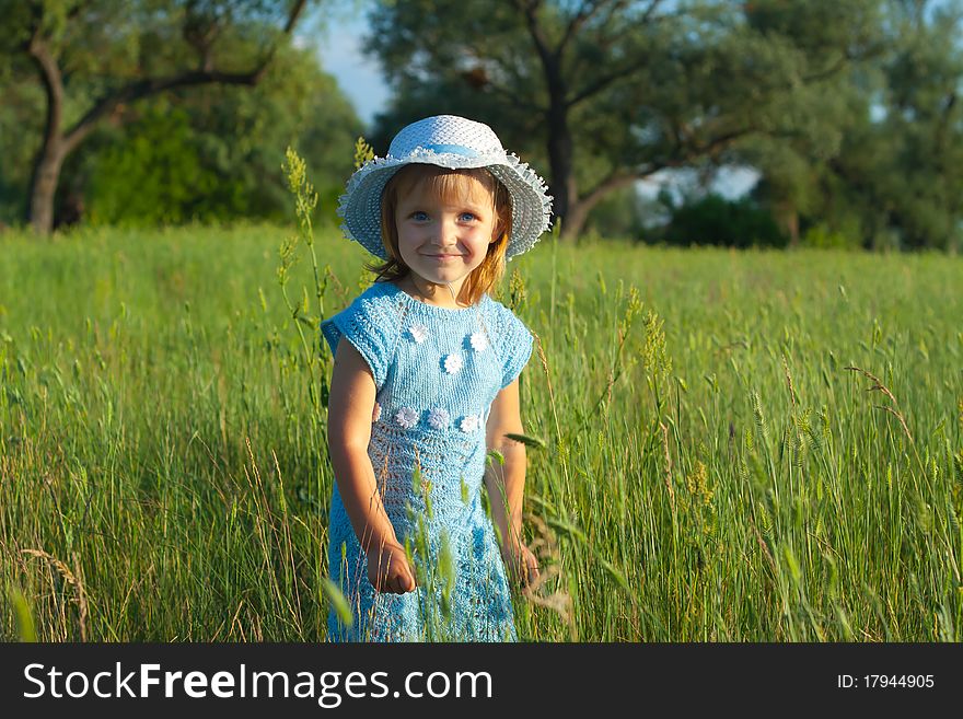 Cute little girl in hat in green grass field. Cute little girl in hat in green grass field