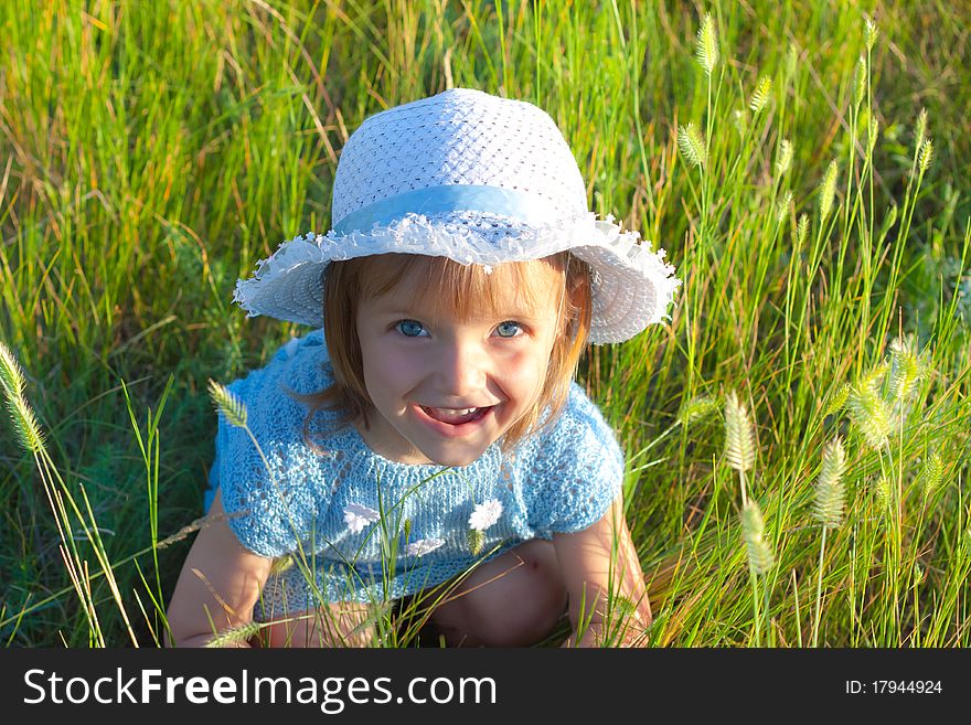 Cute little girl in hat in green grass field. Cute little girl in hat in green grass field