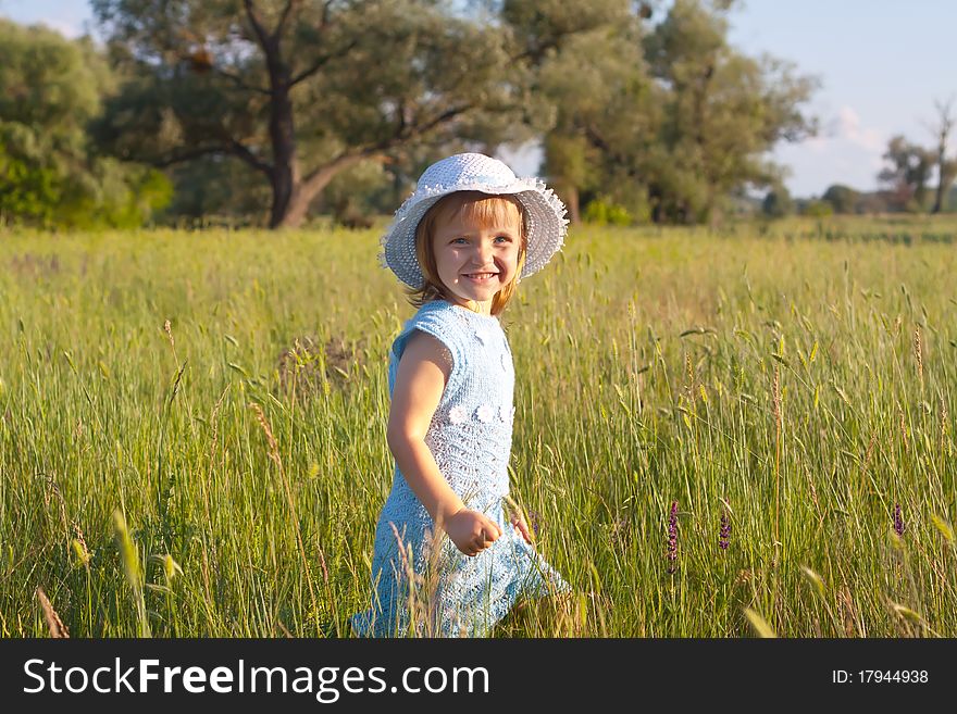 Cute little girl in hat in green grass field. Cute little girl in hat in green grass field