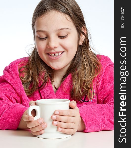 A girl in a colorful robe warms her hands with a mug of hot chocolate. A girl in a colorful robe warms her hands with a mug of hot chocolate