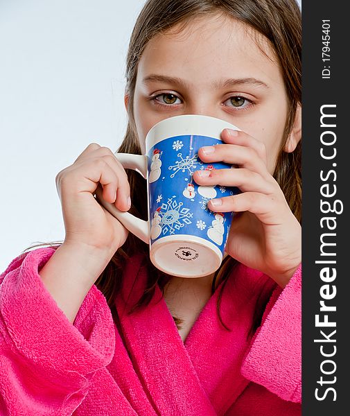 A girl in a pink robe sips from a mug while looking at the viewer. A girl in a pink robe sips from a mug while looking at the viewer