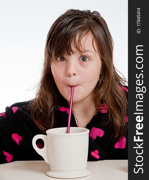A girl sipping from a mug through a straw is surprised. A girl sipping from a mug through a straw is surprised.