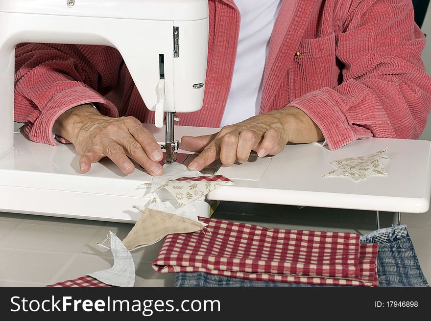 A quilter sews cut pieces of fabric together for quilt top. A quilter sews cut pieces of fabric together for quilt top.
