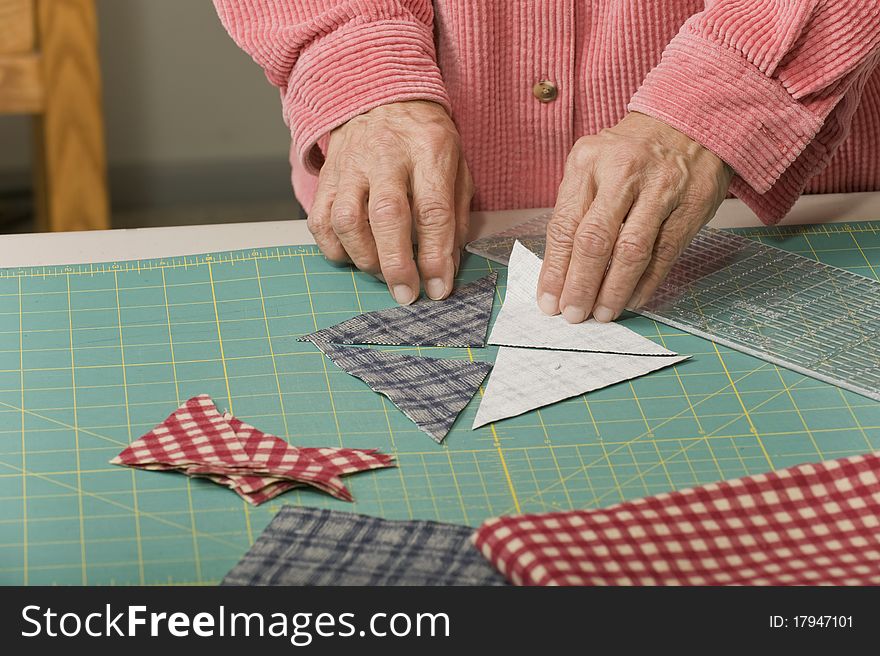 A woman positions four triangle pieces of fabric to make a quilt square. A woman positions four triangle pieces of fabric to make a quilt square.